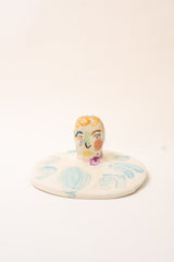 Small ceramic incense holder with hand painted face design on a white background