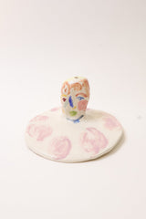 Small ceramic incense holder with hand painted face design on a white background