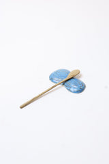a wooden butter spreader and blue ceramic spreader rest