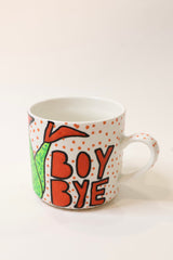 A white ceramic mug with orange polka dots, featuring a green cartoon character and the text 'BOY BYE' in orange with black outlines, set against a plain off-white background.
