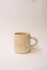 A cream-colored ceramic mug with red line-art of a cat, photographed against a plain white background.