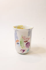 Ceramic cup with colorful child-like drawings on a white background