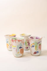 Colorful ceramic mug with hand painted face design on a white background