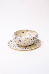 A cream-colored ceramic wall sconce with blue abstract calligraphic patterns, shown from an angled side view against a plain white background.